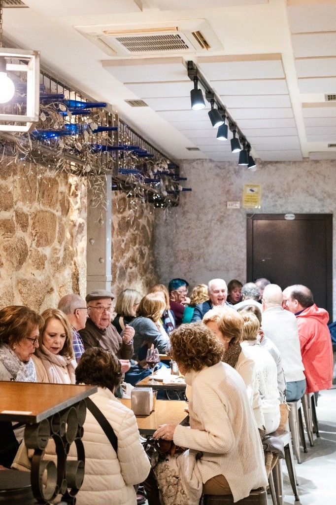 Salón con clientes junto al muro de piedra