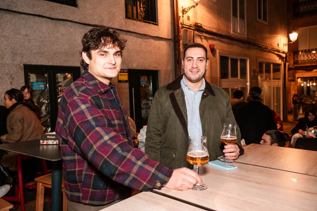 Dos clientes con cerveza en mesa alta de terraza