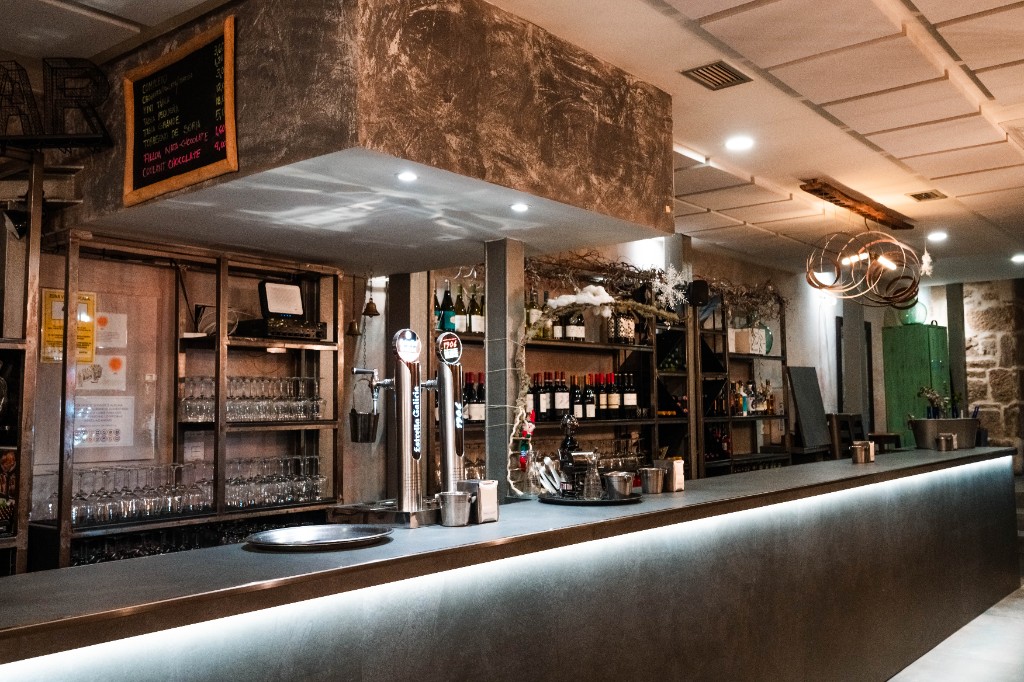 Barra con grifos de cerveza y estantería de vinos